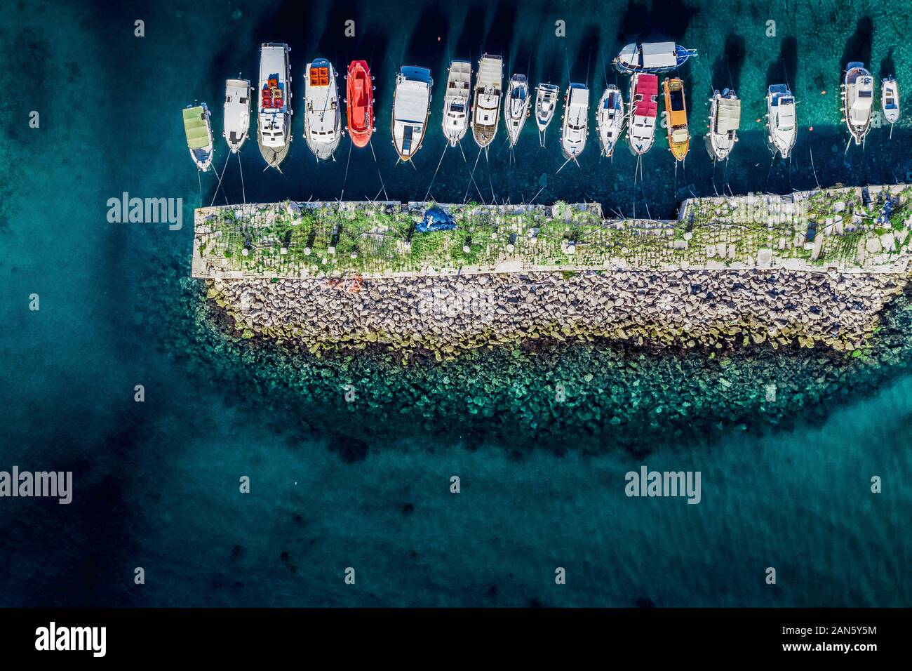 Aerial drone top-down view of boats and breakwater on the harbor of Dubrovnik Old Town. Bird-eye view Croatian port with clear water. Stock Photo