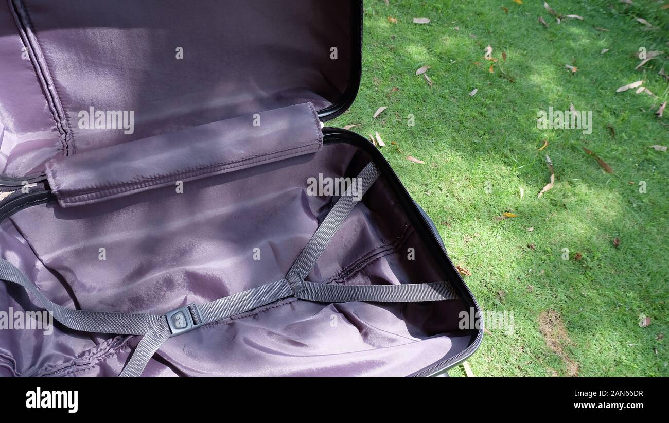 A travelling suitcase opened and being aired under the sun, with green lawn in the background. Stock Photo