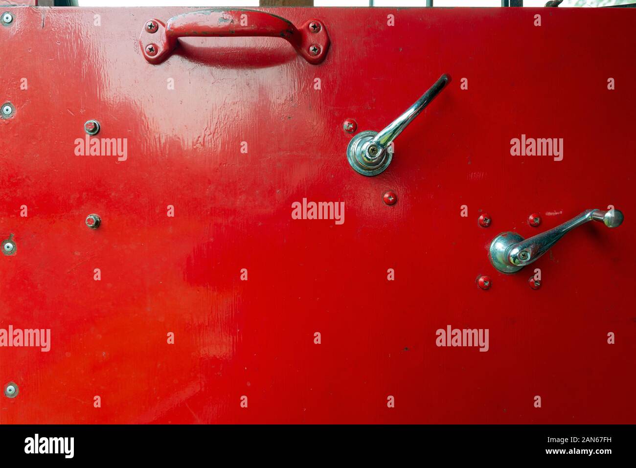 A Red Metal Door of an Old Fire Truck with Window Crank and Handles Stock Photo