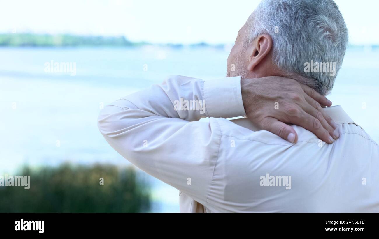 Senior businessman touching aching neck, sedentary lifestyle consequences Stock Photo