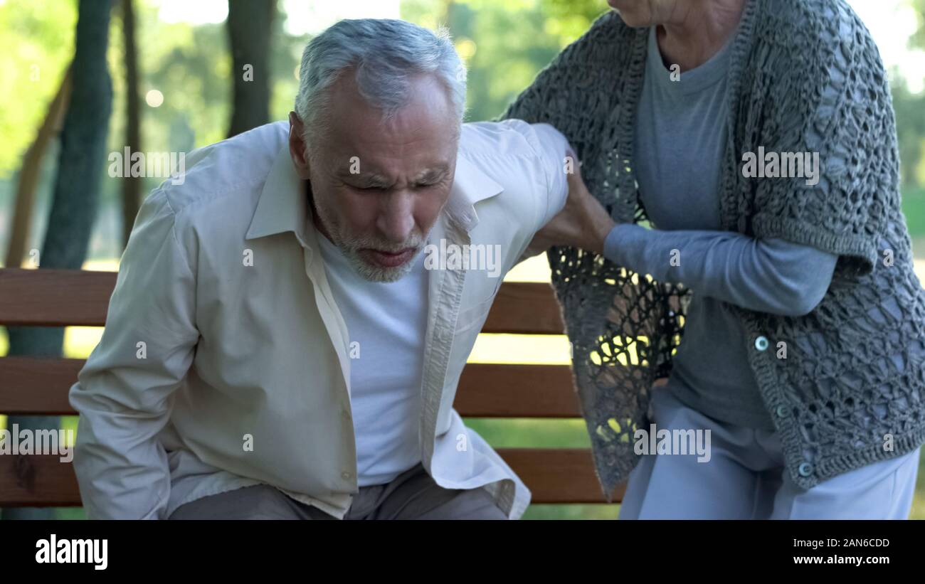 Old man has spine problems, vertebral hernia, caring wife supporting him, health Stock Photo