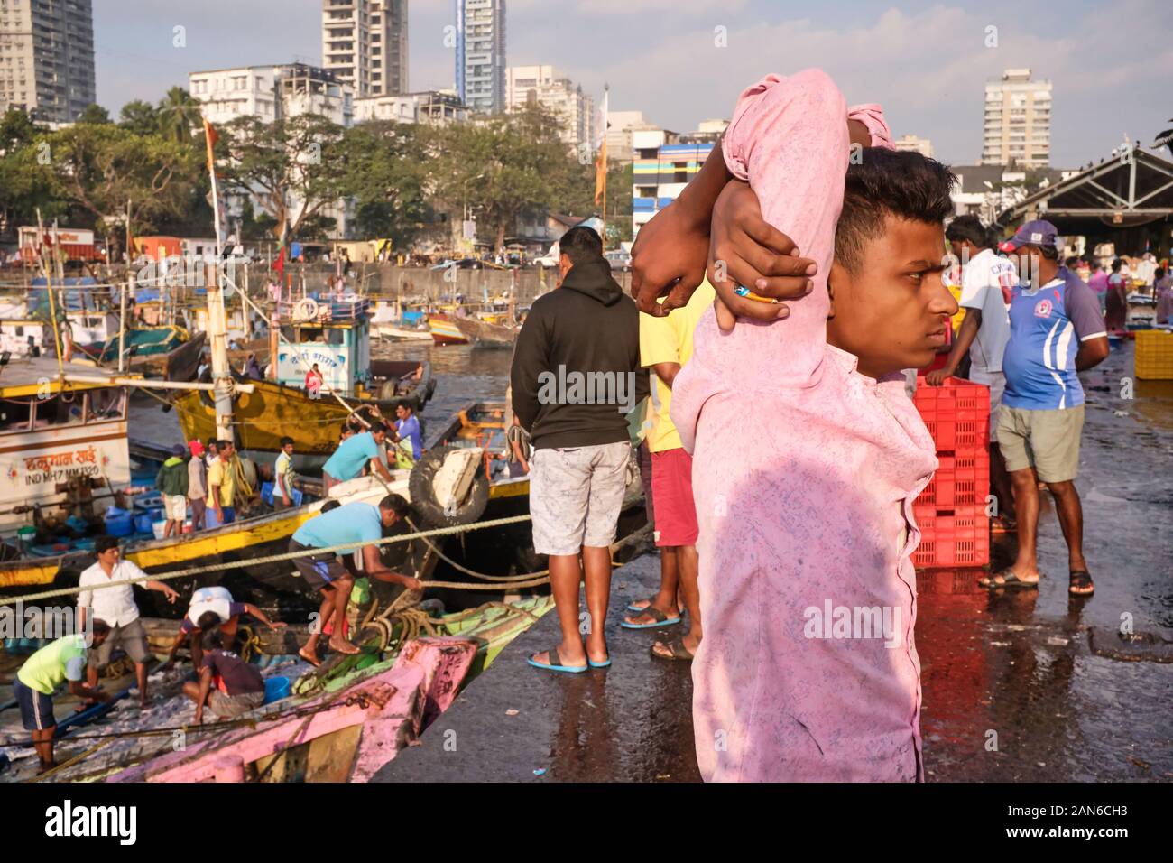 A fisherman at Sassoon Docks, in Colaba, Mumbai, India, having returned from a fishing trip and standing in a kind of odd resting position Stock Photo