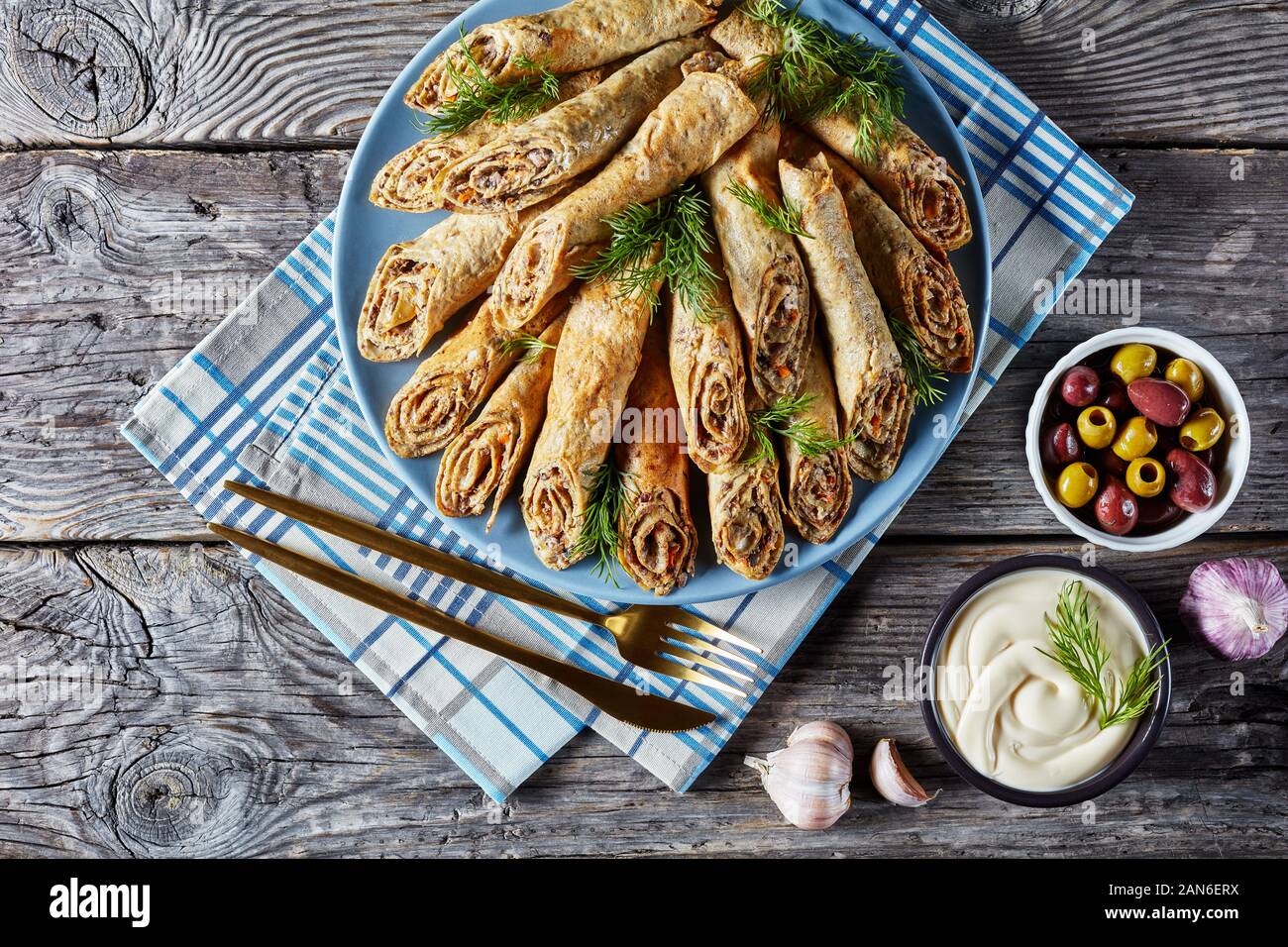 buckwheat crepes rolls with meat, vegetables and mushrooms fillings on a plate on a old rustic wooden table, view from above, flat lay Stock Photo