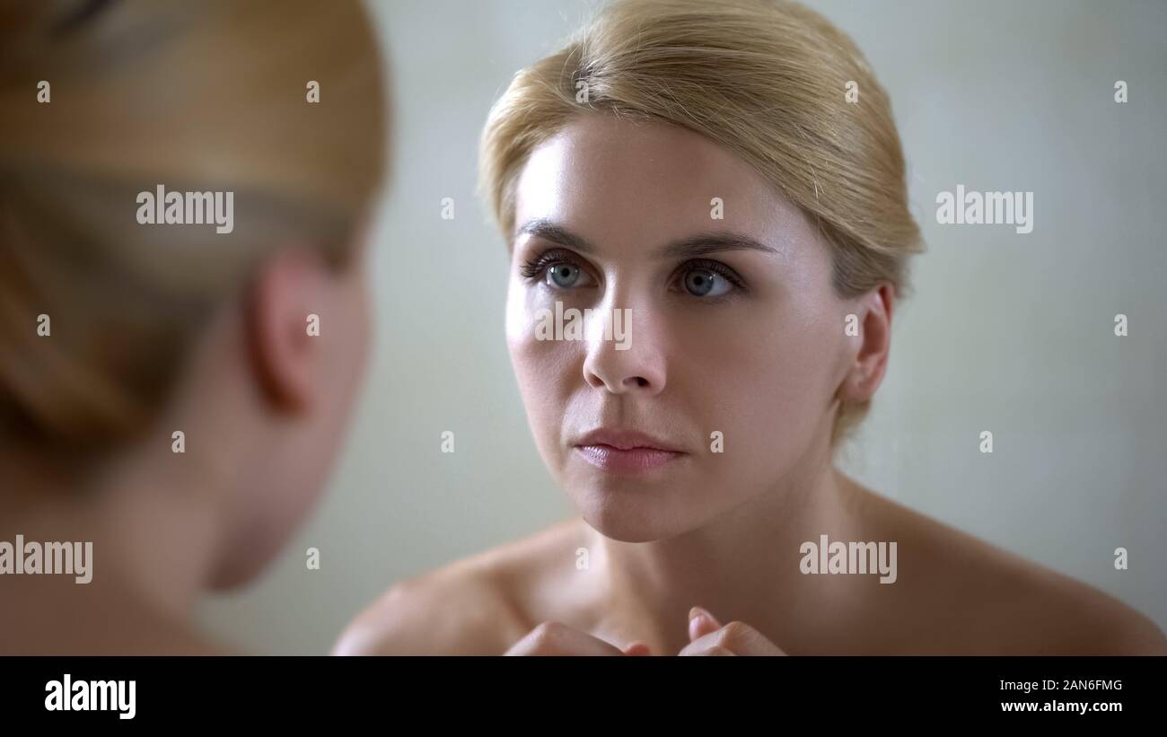 Portrait of beautiful lady looking at mirror reflection, anti-aging cream effect Stock Photo