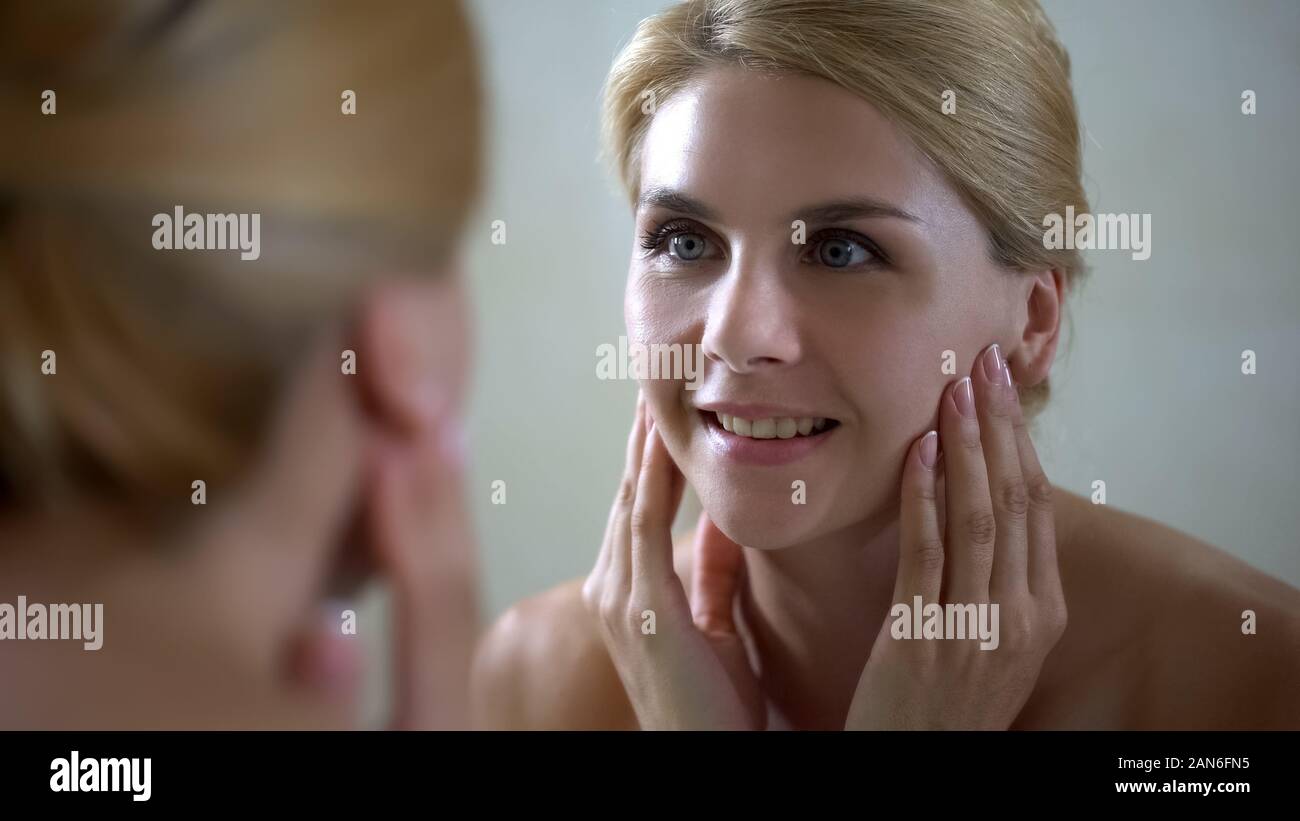 Middle aged woman satisfied with face condition after beauty therapist visit Stock Photo