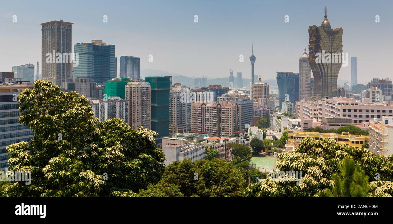 Panorama of Macao skyline - with residential buidlings, Hotel Grand Lisboa and Macao Tower. Green trees in the foreground. Stock Photo