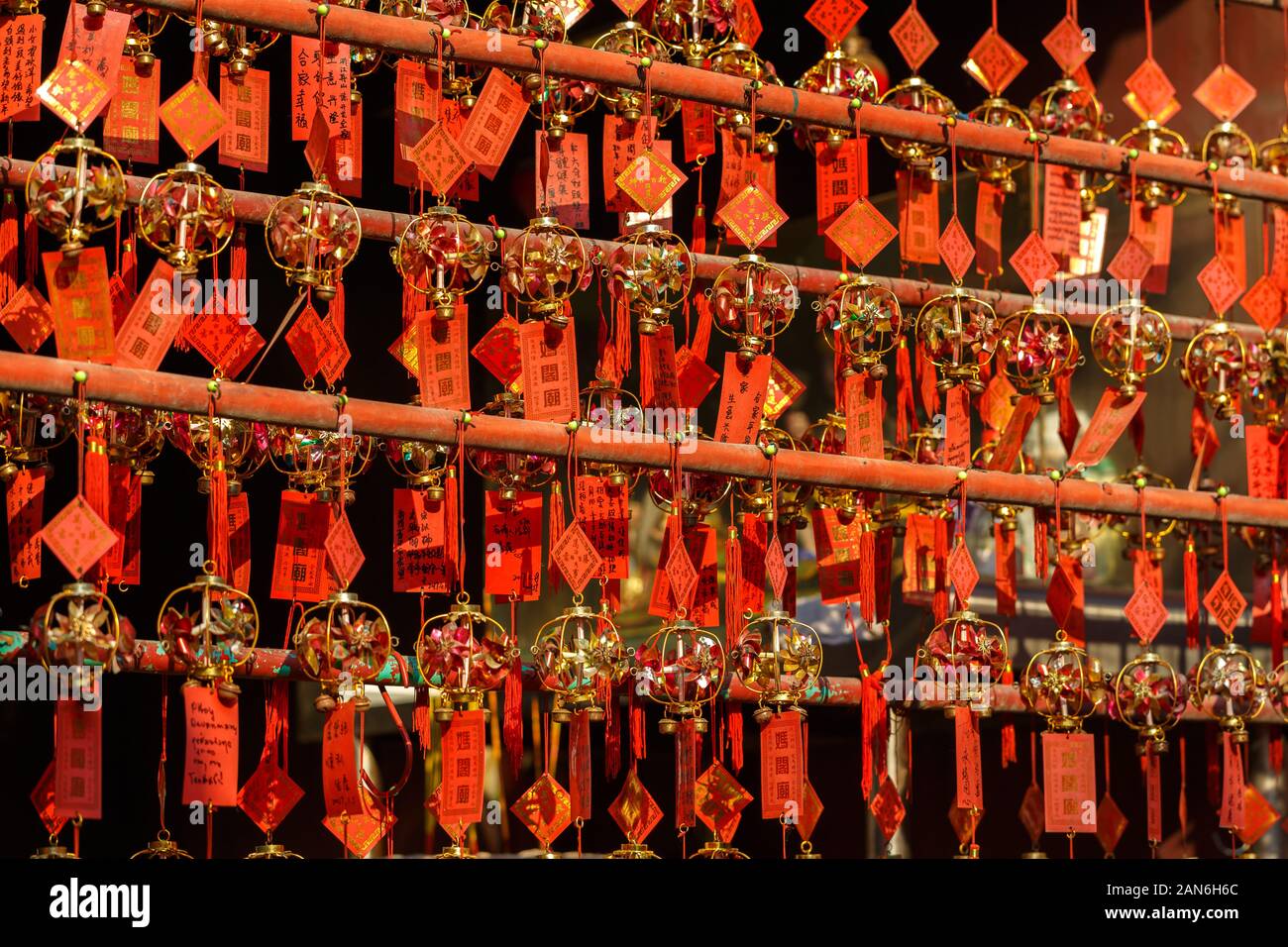 Red colored prayer cards at A-Ma temple. All lined up in rows and hanging on bars. The cards are artistically decorated with bells. Stock Photo