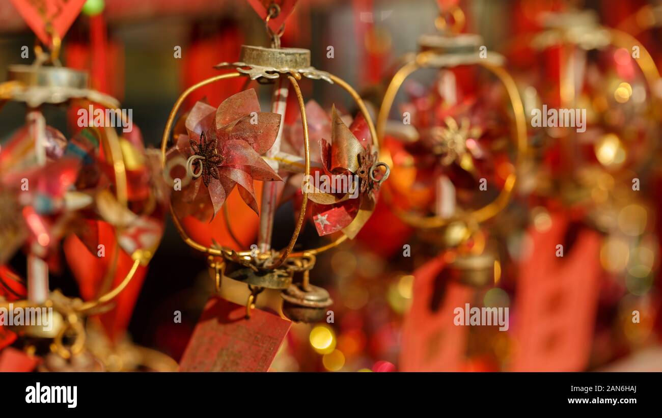 Close-up of decoration of buddhist wish / prayer cards. Round, golden colored structure with red paper flowers and a bell. For luck and good fortune. Stock Photo