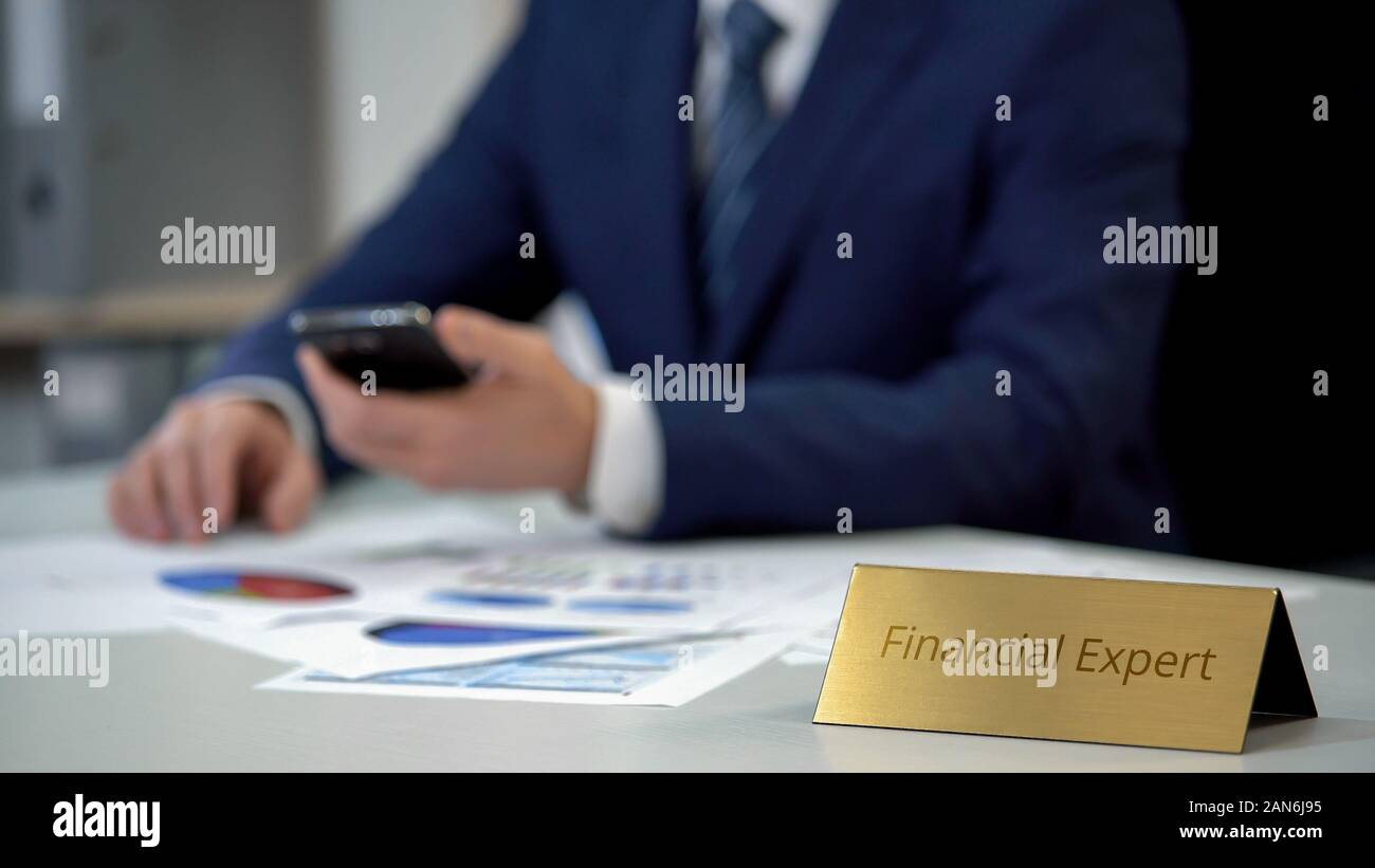 Young financial expert analyzing business documents, using mobile application Stock Photo