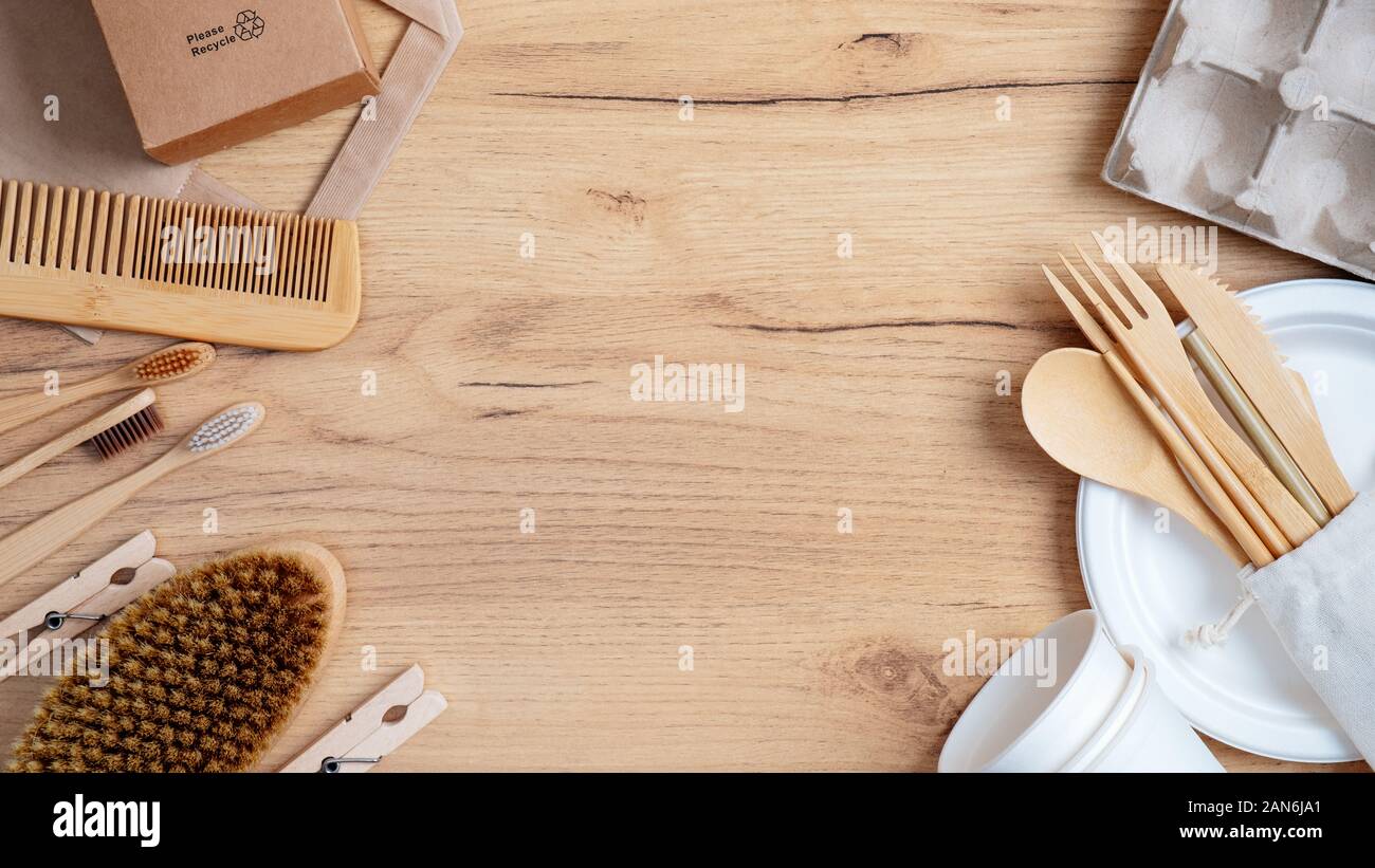 Frame of bamboo cutlery, carton eggs box, cosmetic brush, toothbrushes, hair comb, wooden pins and other natural eco-friendly items on wooden table. Z Stock Photo
