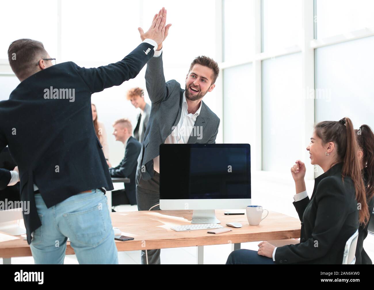 young employees giving each other a high five Stock Photo - Alamy