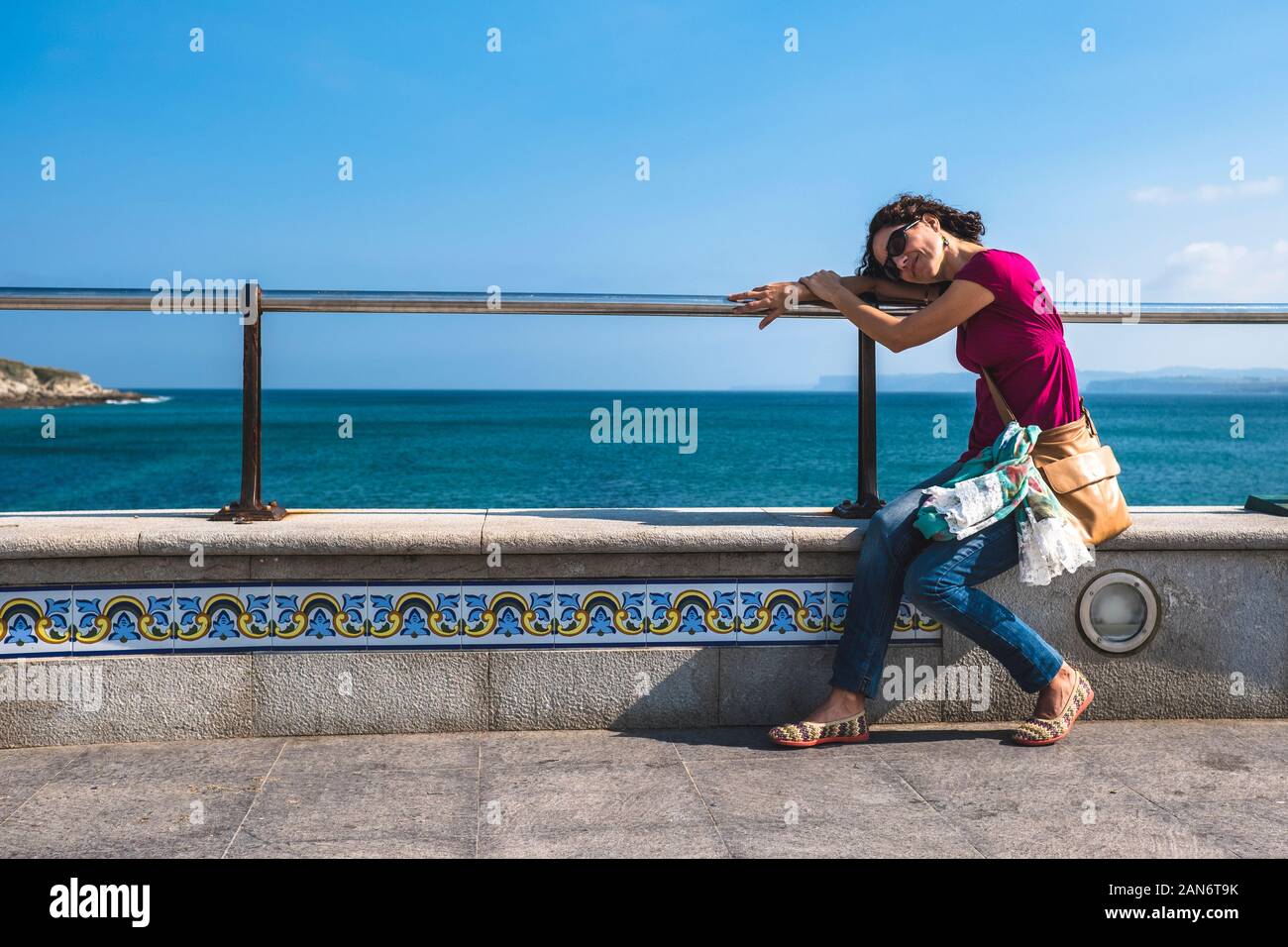 Resting On Railing Woman resting on a railing by the sea Stock Photo - Alamy