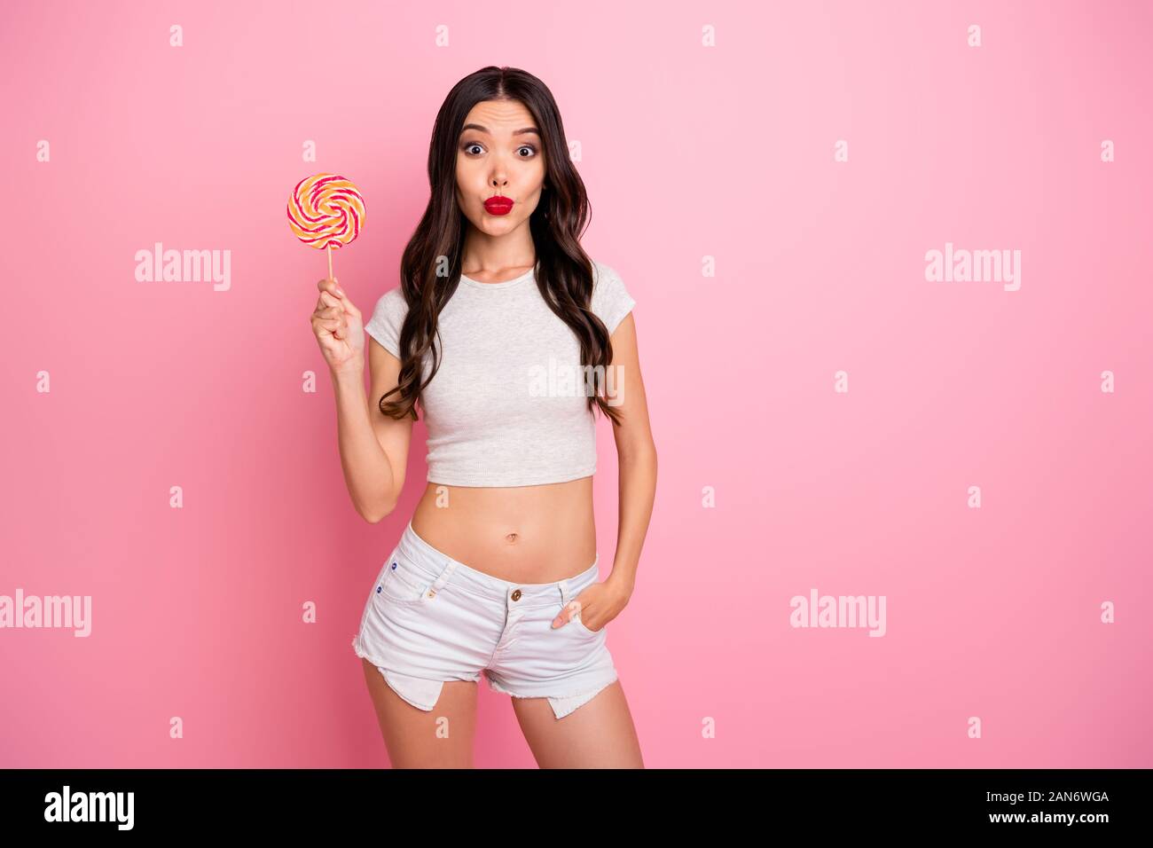 Portrait of her she nice attractive lovely charming amazed cheerful cheery wavy-haired girl licking lolly pop having fun pout lips isolated over pink Stock Photo
