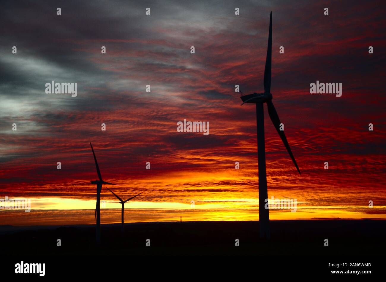 Wind turbines in the UK silhouetted against sunset. Sustainable energy production icons. Stock Photo