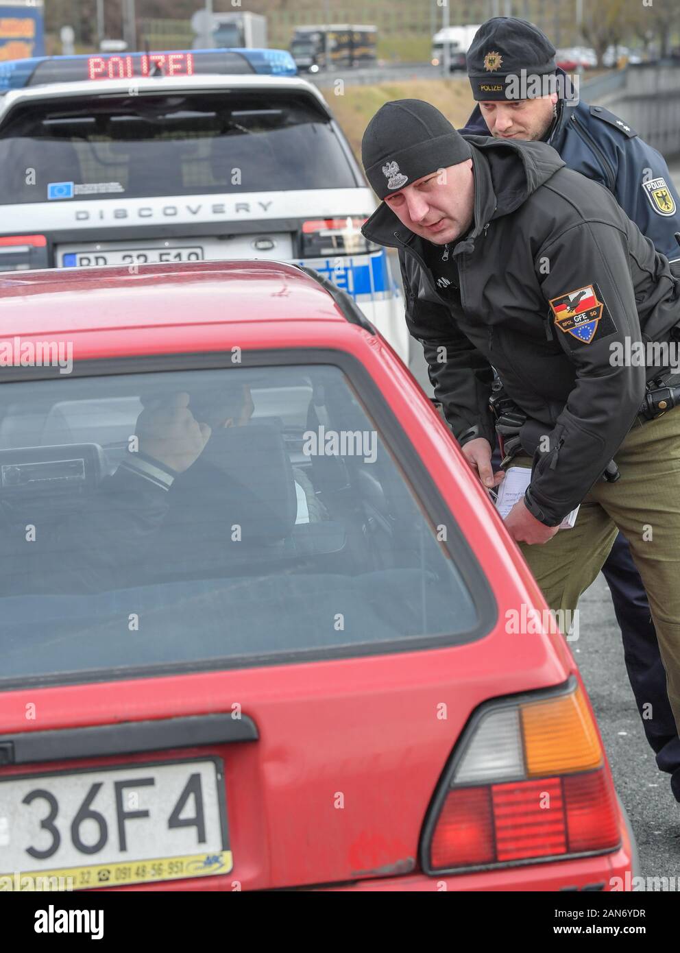 14 January 2020, Brandenburg, Frankfurt (Oder): Sven Umland (back), Chief Police Commissioner at the Federal Police and Damian Kuzynin, from the Polish Border Guard, check travellers in a car on Autobahn 12 shortly before the Polish border. German and Polish border guards are patrolling the Oder and Neisse rivers together, and since the autumn they have also been patrolling in new official vehicles. Nevertheless, the fight against transnational crime remains arduous, not least because of the density of traffic. Photo: Patrick Pleul/dpa-Zentralbild/ZB Stock Photo