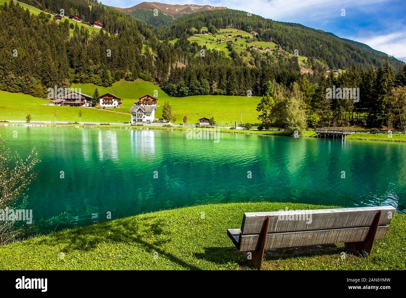 Wooden bench in front of the Mühlwald reservoir in Mühlwald South Tyrol Italy Stock Photo
