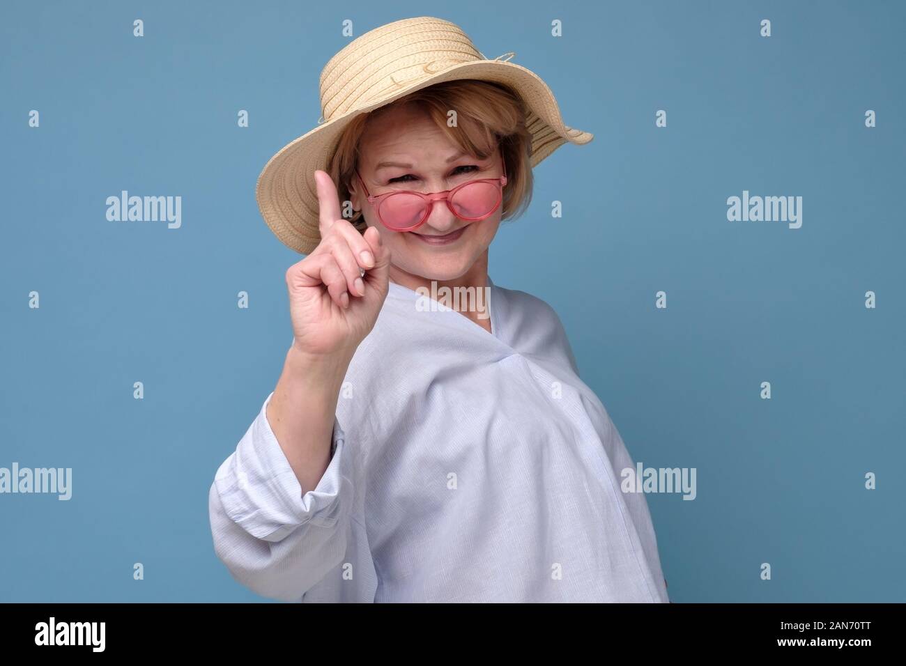 I got excellent advice for daughter. Excited and enthusiastic creative senior woman in summer hat and pink glasses raising index finger in eureka gest Stock Photo