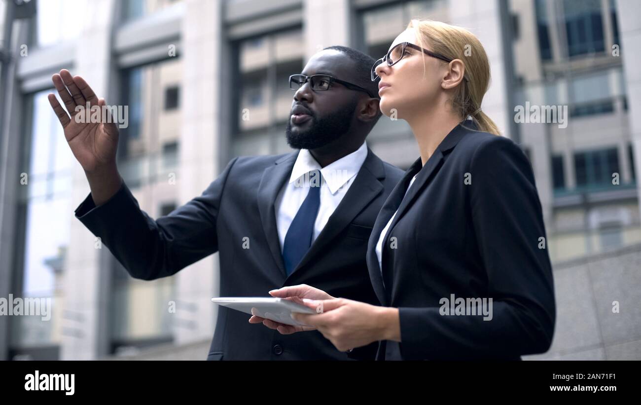 Architects compare project on tablet with construction site, high-rise building Stock Photo