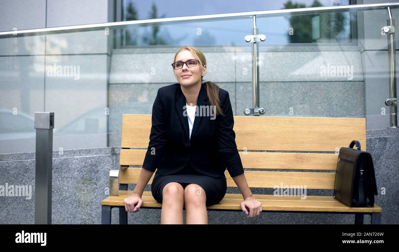 Smiling businesswoman sitting on bench, relaxing after stressful working day Stock Photo