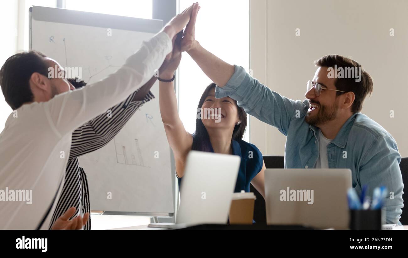 Overjoyed diverse employees give high five at office meeting Stock ...