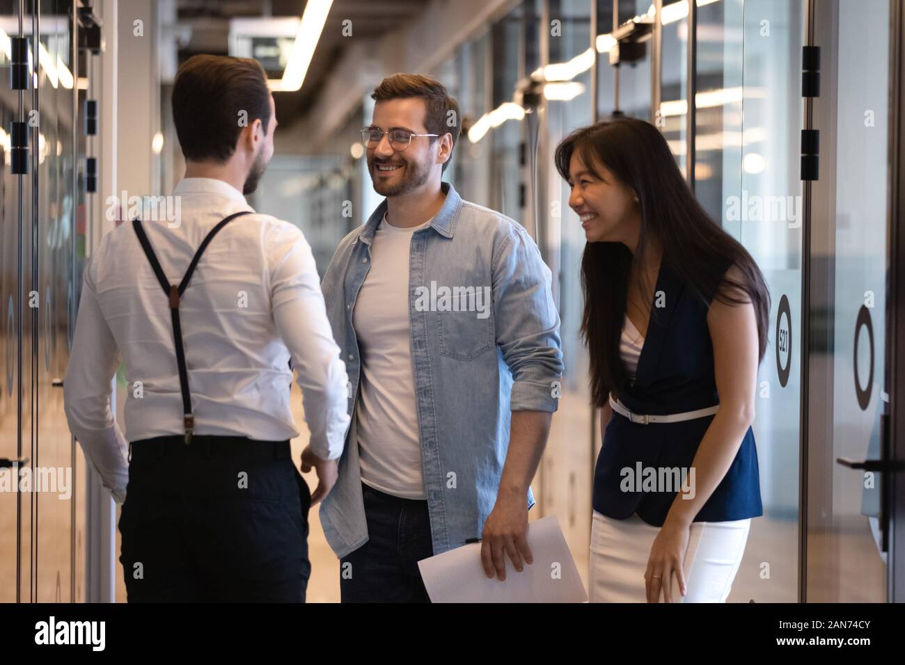 Happy multiethnic coworkers chatting in modern office corridor Stock Photo