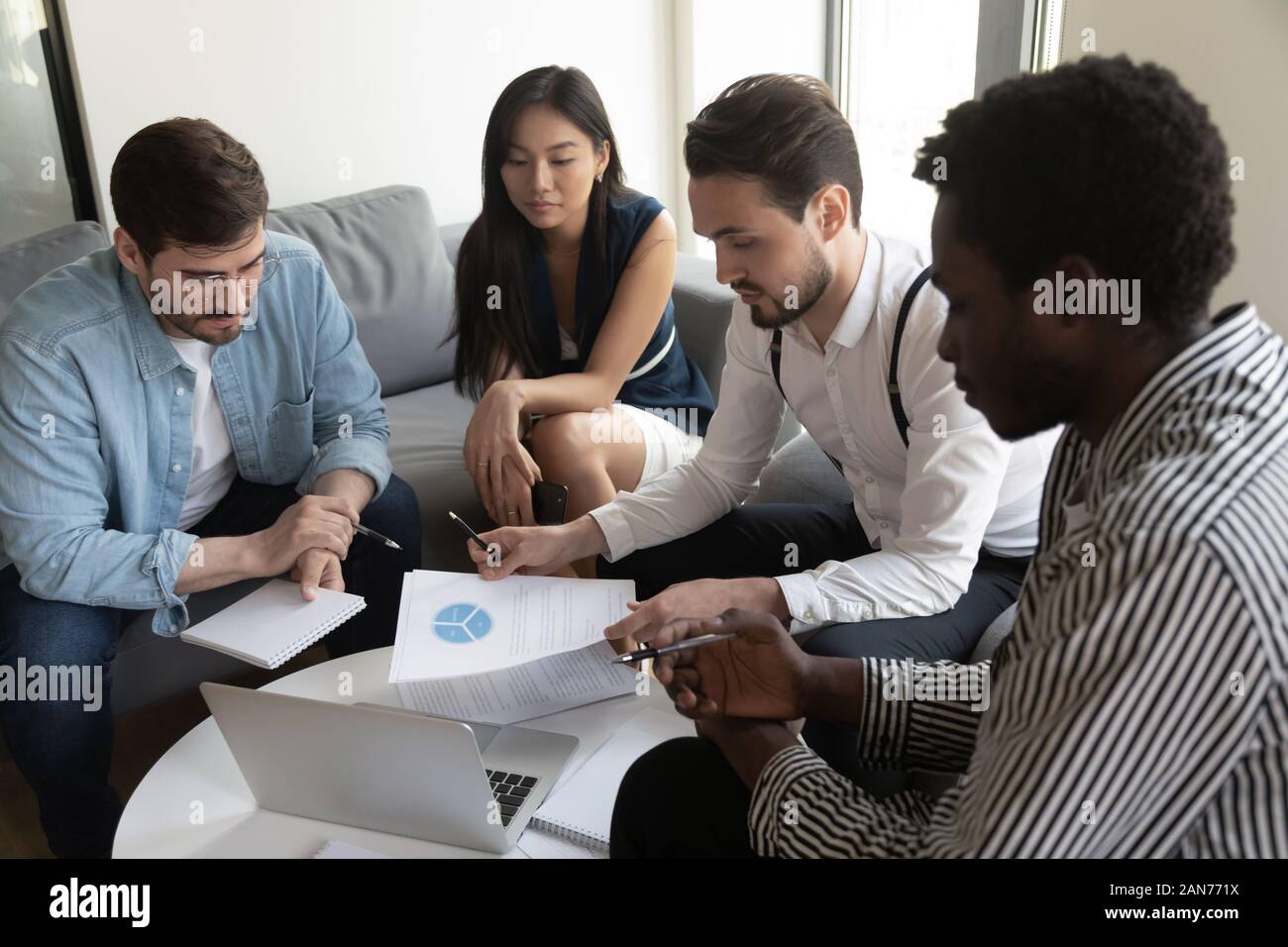 Multiethnic businesspeople brainstorm discussing paperwork at meeting Stock Photo