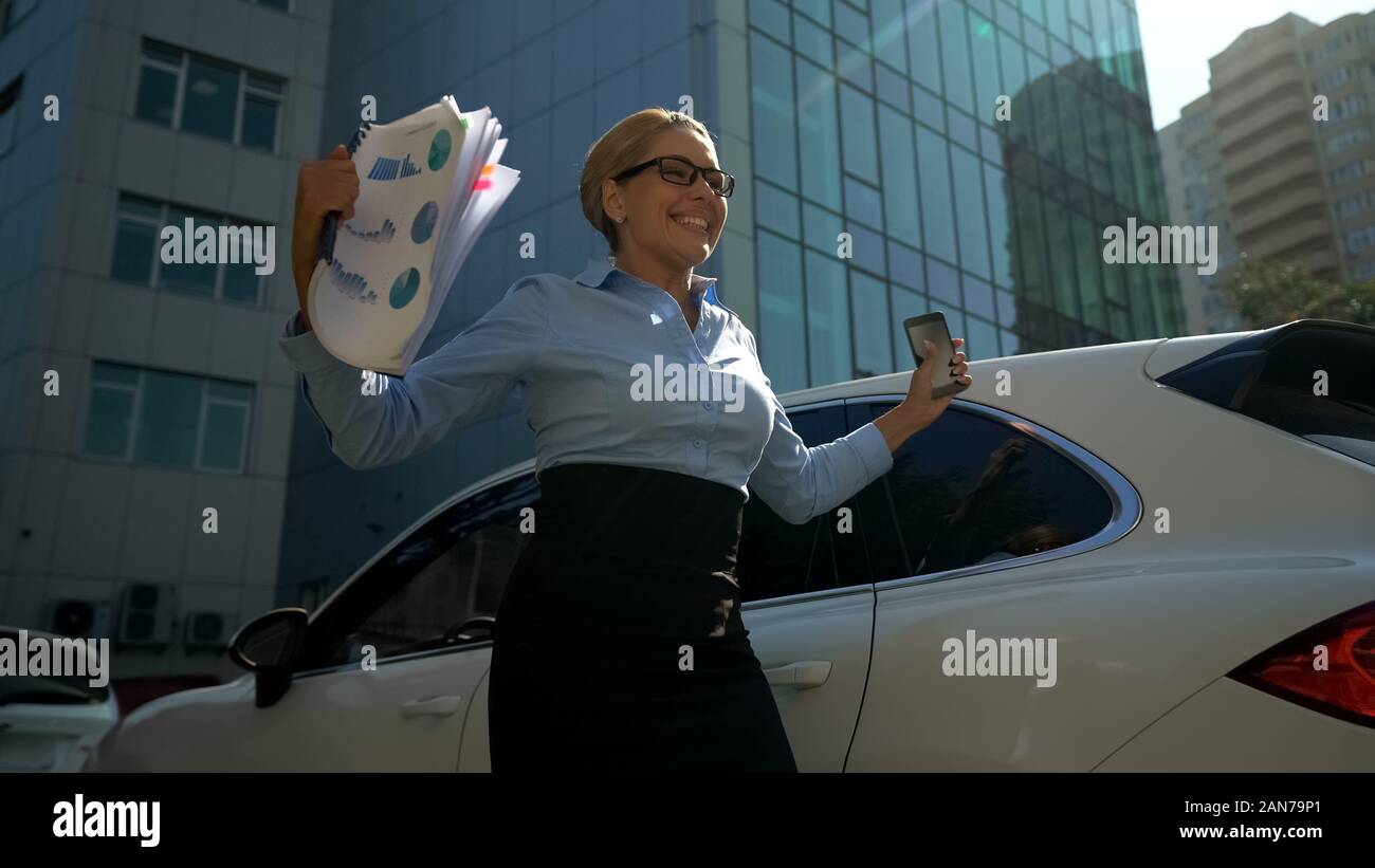 Businesslady happy with investment reads message of successful tranche on phone Stock Photo
