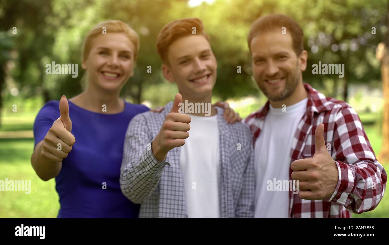 Cheerful family smiling showing thumbs-up, lucrative loans, credits for studying Stock Photo