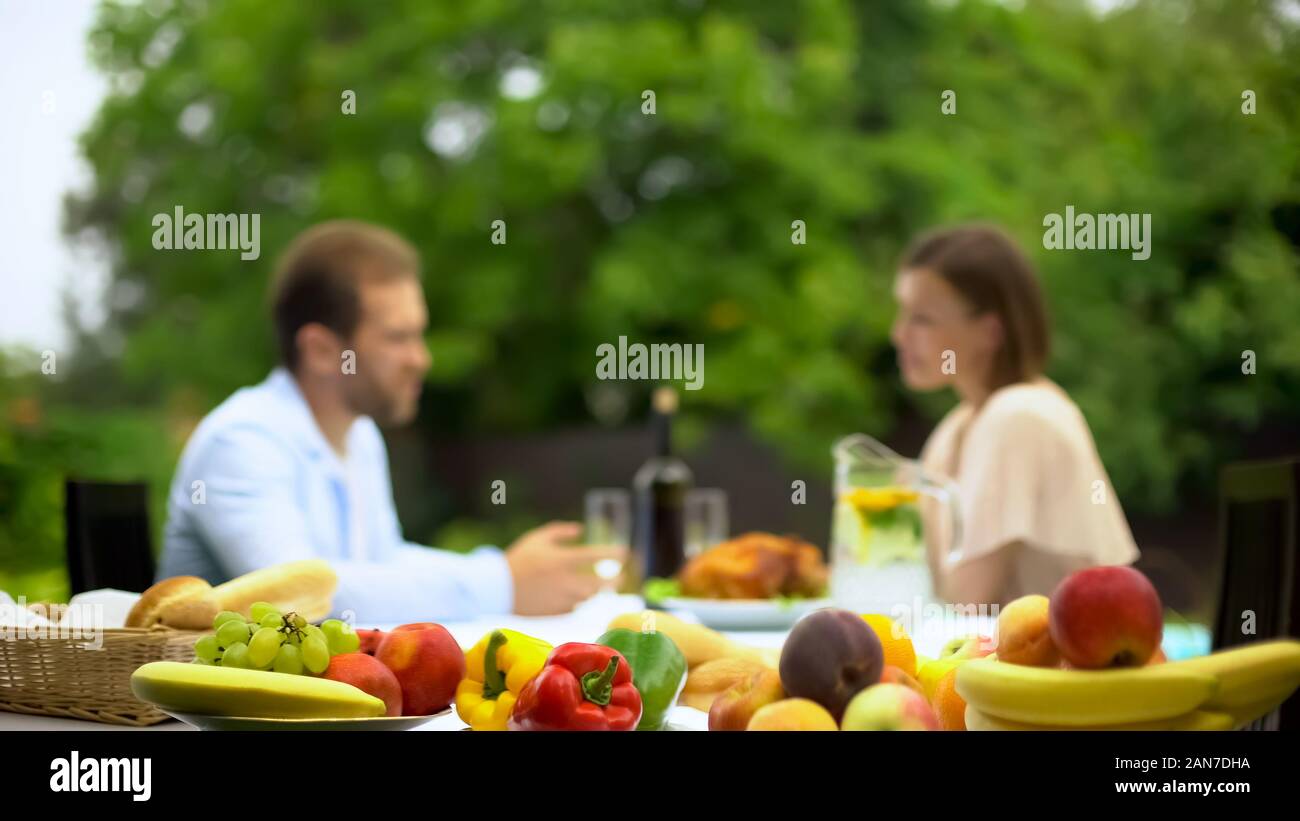 Young couple talking while having lunch, non gmo fruits, pesticide free food Stock Photo
