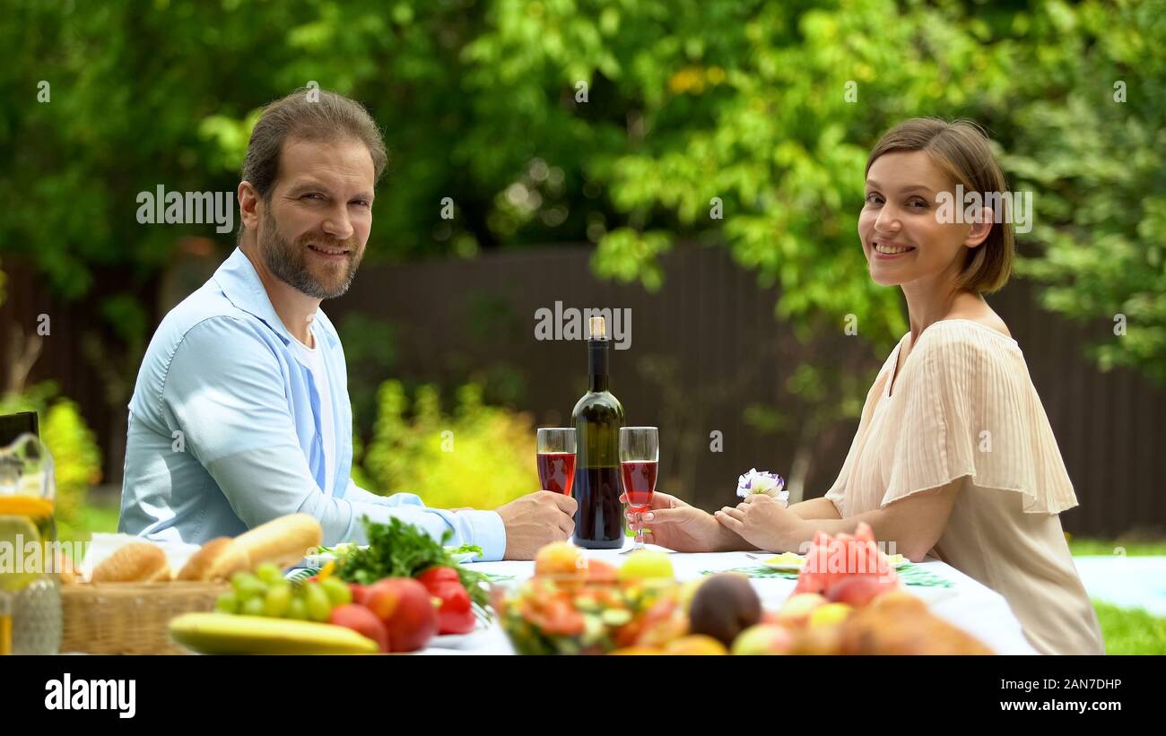 Cheerful couple holding wine glasses and looking at camera, healthy lifestyle Stock Photo