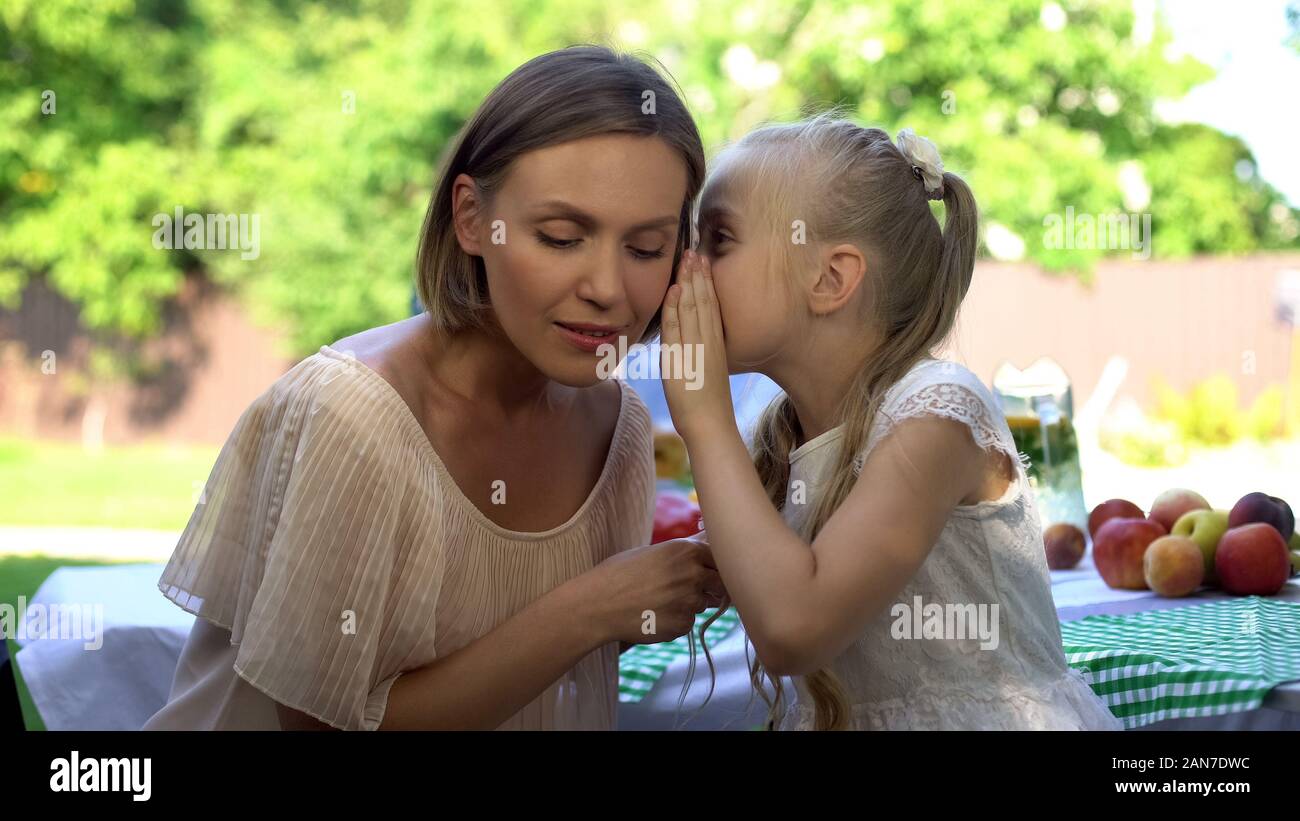 Cheerful daughter sharing secret with mother, telling about first love, trust Stock Photo