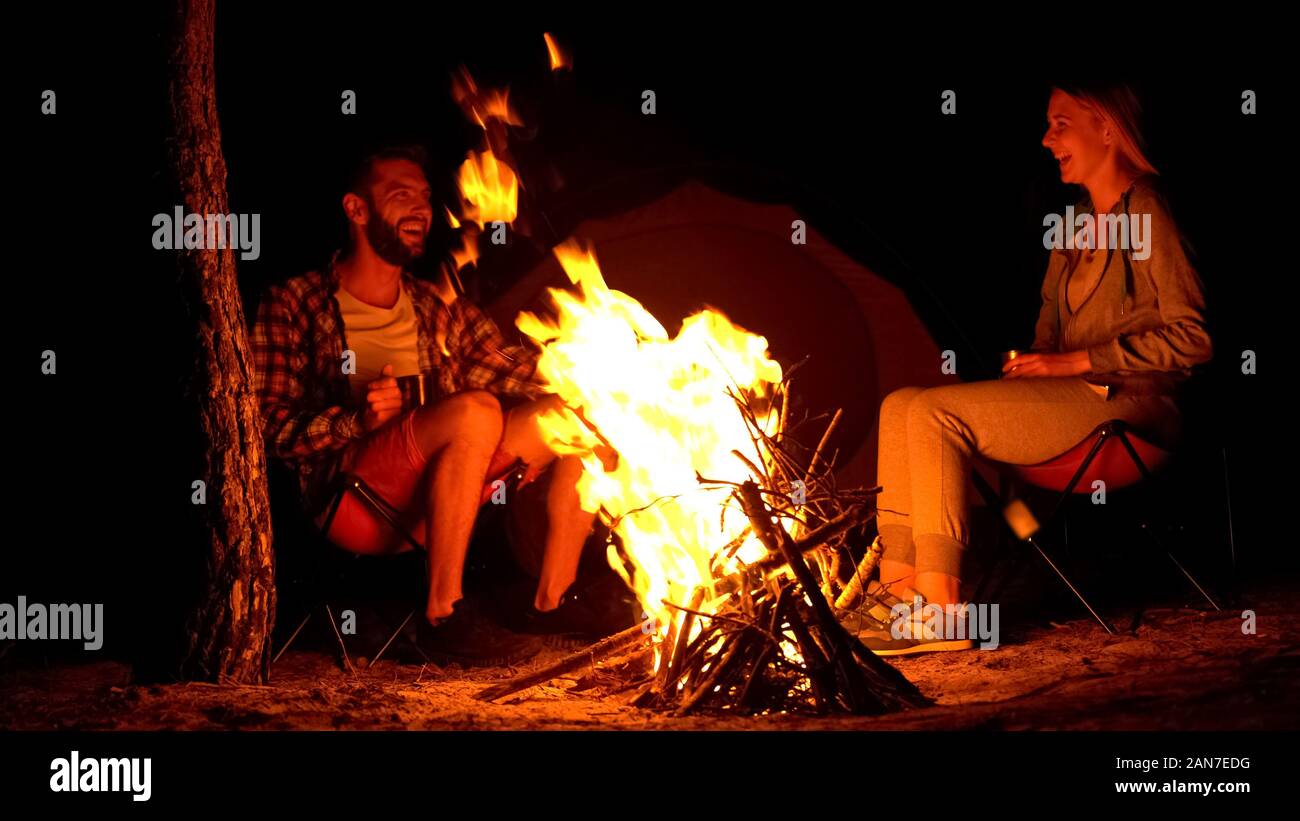 Two campers warming up near campfire, telling funny stories, wild fire risk Stock Photo - Alamy Two campers warming up near campfire, telling funny stories, wild fire risk Stock Photo - Alamy