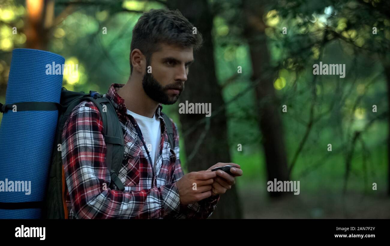 Man orienteering in forest, using navigational compass, survival classes Stock Photo
