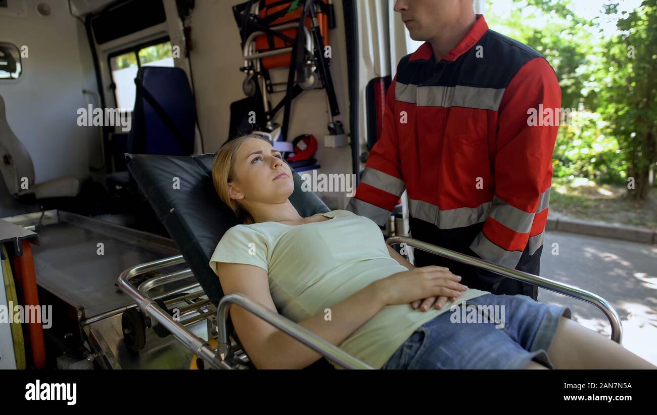 Paramedics carrying patient on stretcher into ambulance, fast qualified