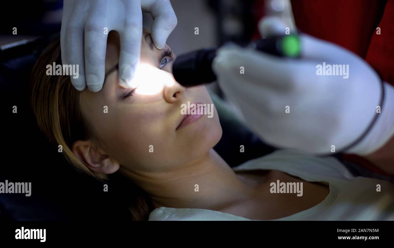 Doctor shining light into patient eye, testing pupil reflexes, first aid closeup Stock Photo