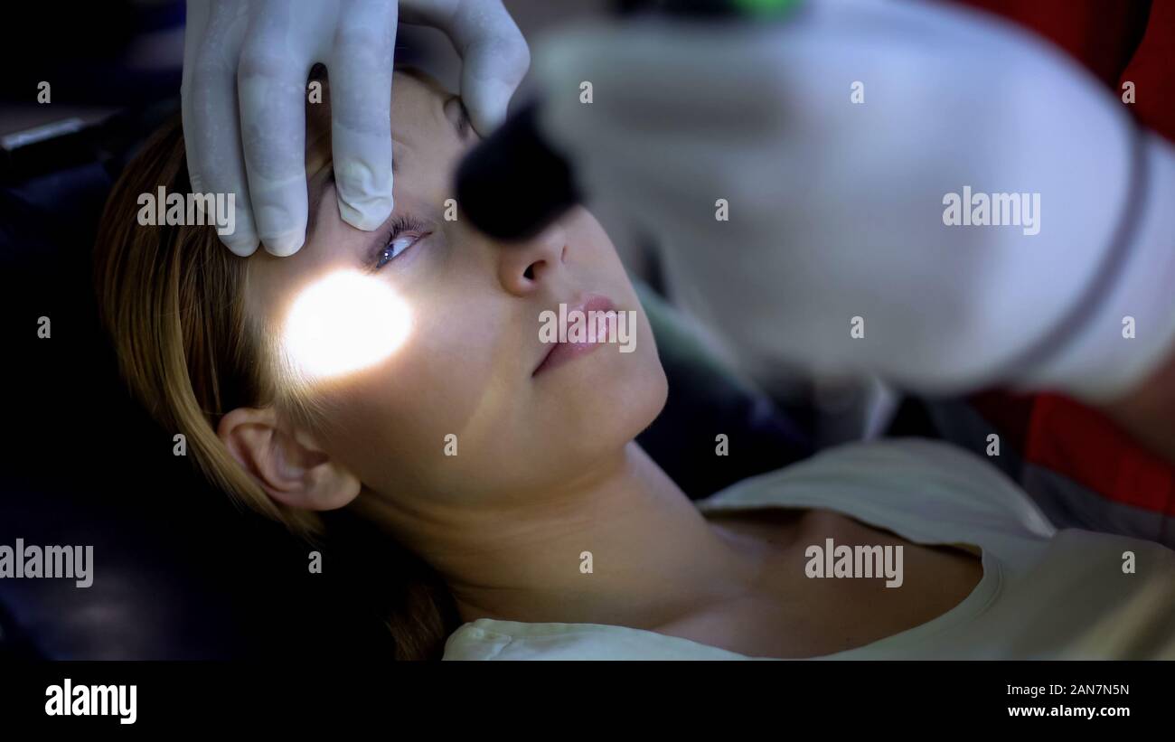 Paramedic shining light into patient eyes, testing pupil reflexes, first aid Stock Photo