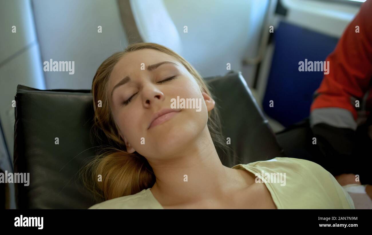 Pale girl lying unconscious in ambulance, paramedic transfers patient to clinic Stock Photo