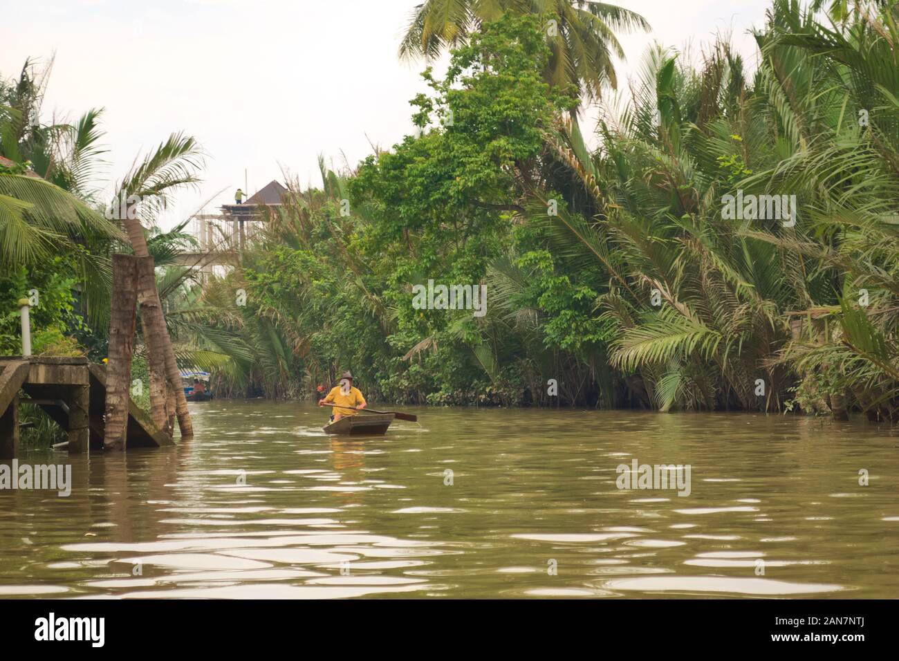 Man rowing on a boat along one of the tributaries of Mekong River near ...