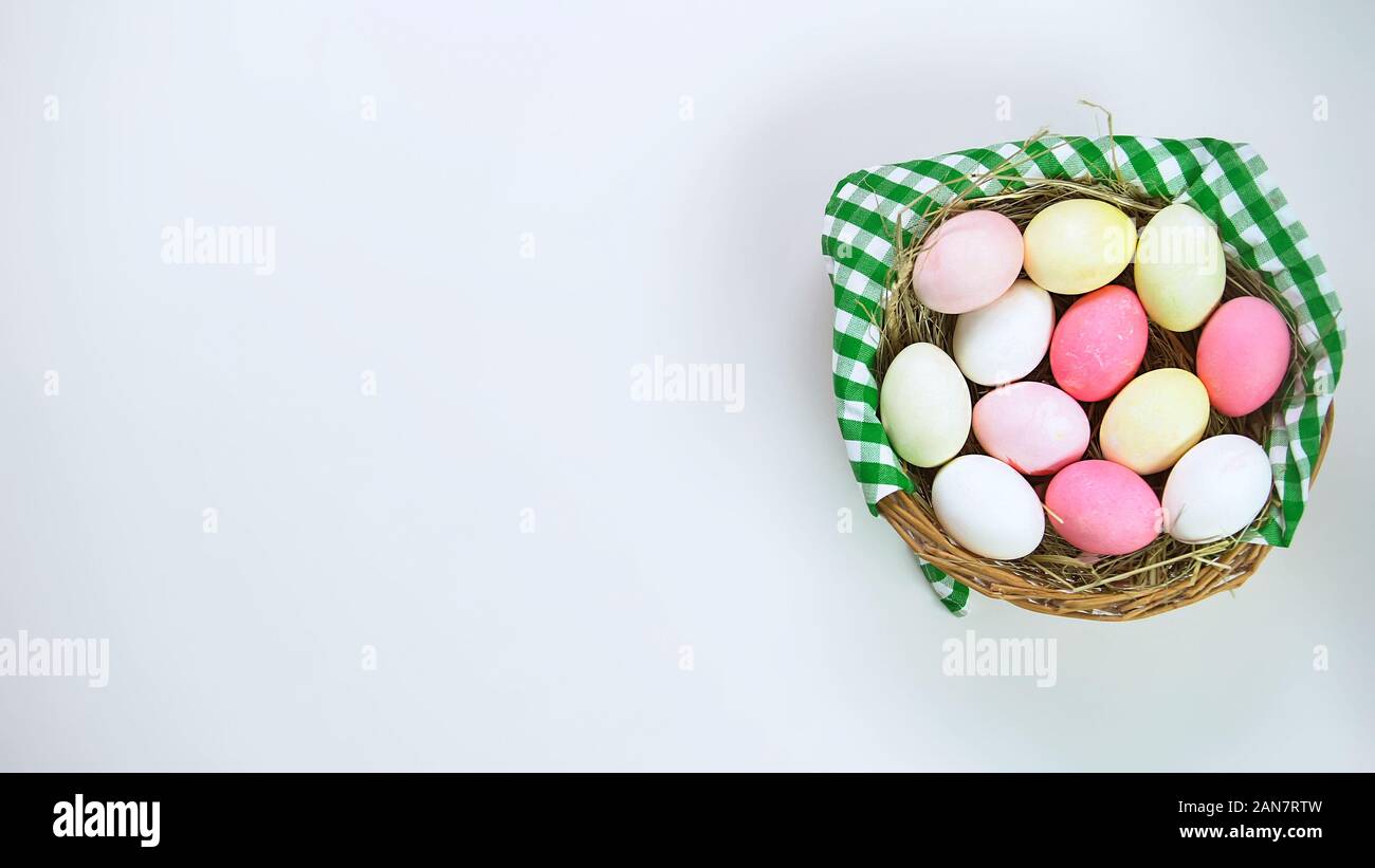 Basket of colored Easter eggs standing on white table, holiday celebration Stock Photo