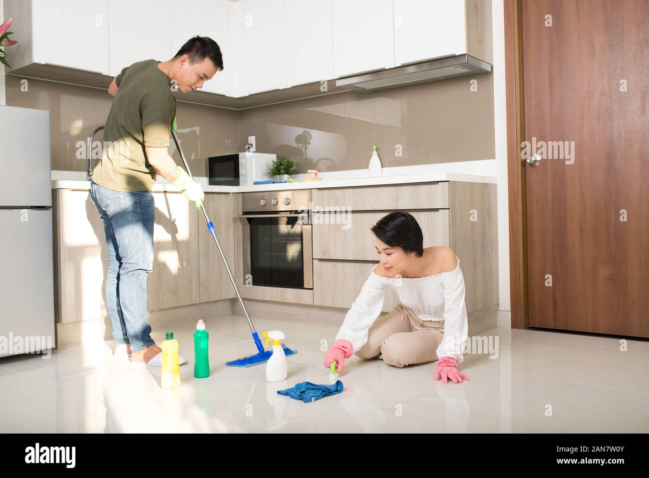 Young happy Asian couple is having fun while doing cleaning at home. Stock Photo