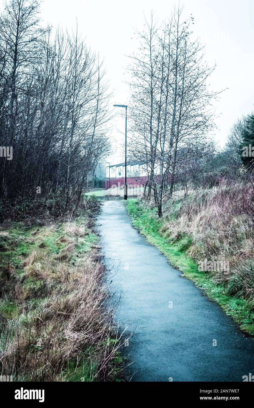 A path through run down and desolate urban wasteland, towards modern houses, Newcastle upon Tyne, Tyne and Wear, United Kingdom Stock Photo