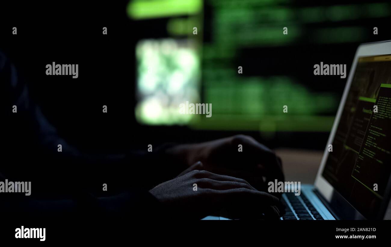 Programmer writing code for malware, remote hacking of bank accounts, cybercrime Stock Photo