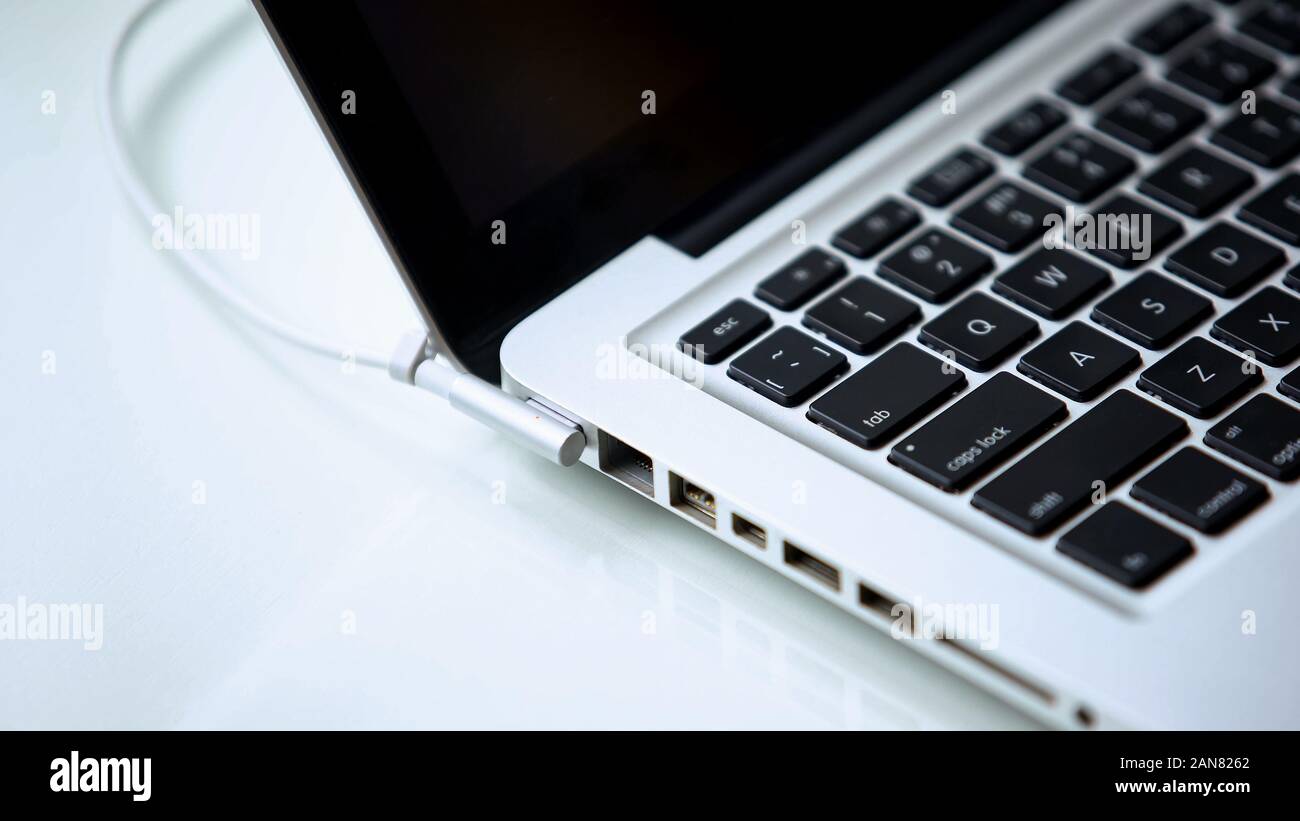 Laptop power adapter plugged in, gadget recharging, office work