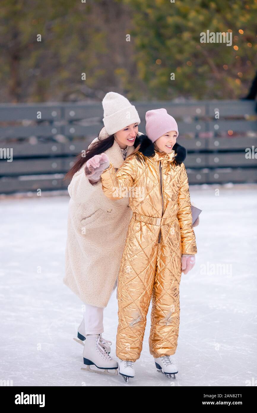 Little adorable girl with her mother skating on icerink. Family winter