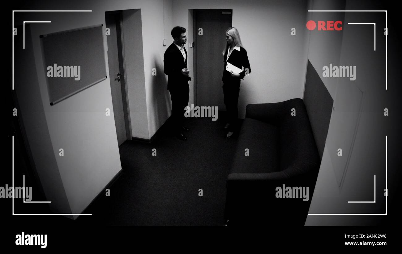 Male and female colleagues talking office corridor, CCTV camera effect,  footage Stock Photo - Alamy