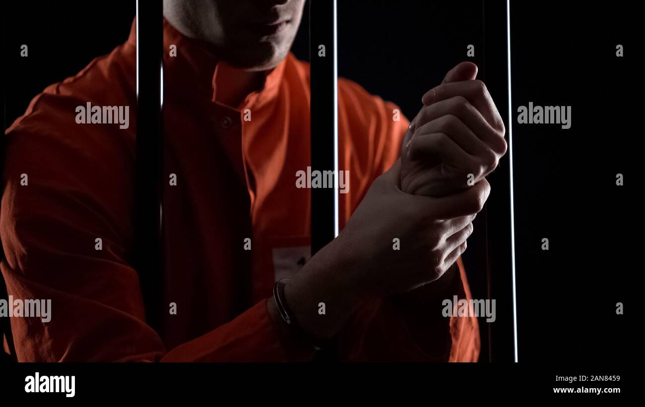 Inmate in handcuffs rubbing wrists, inhuman conditions and tortures in prison Stock Photo