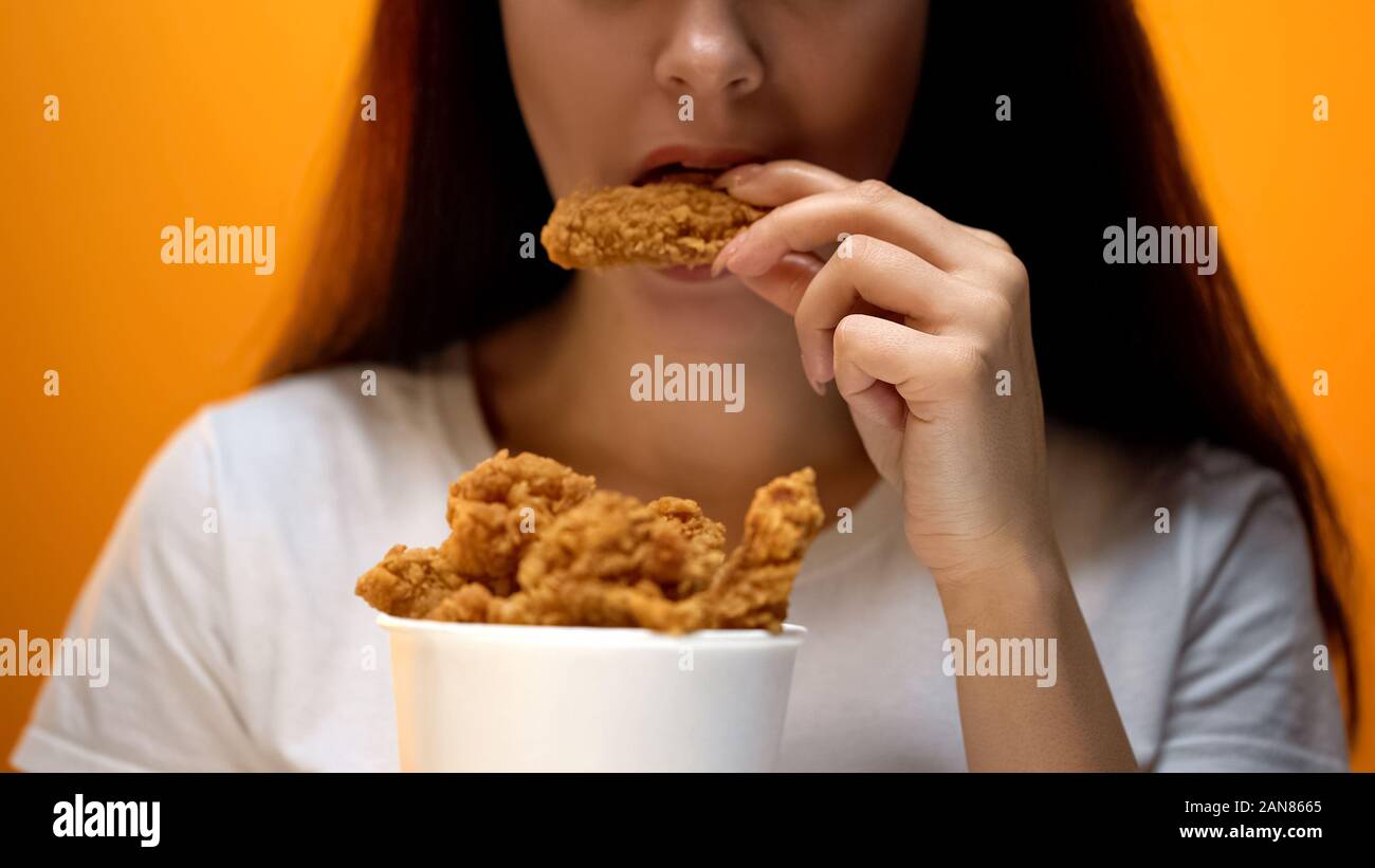 Girl eating chicken wings, high calorie food and health risks
