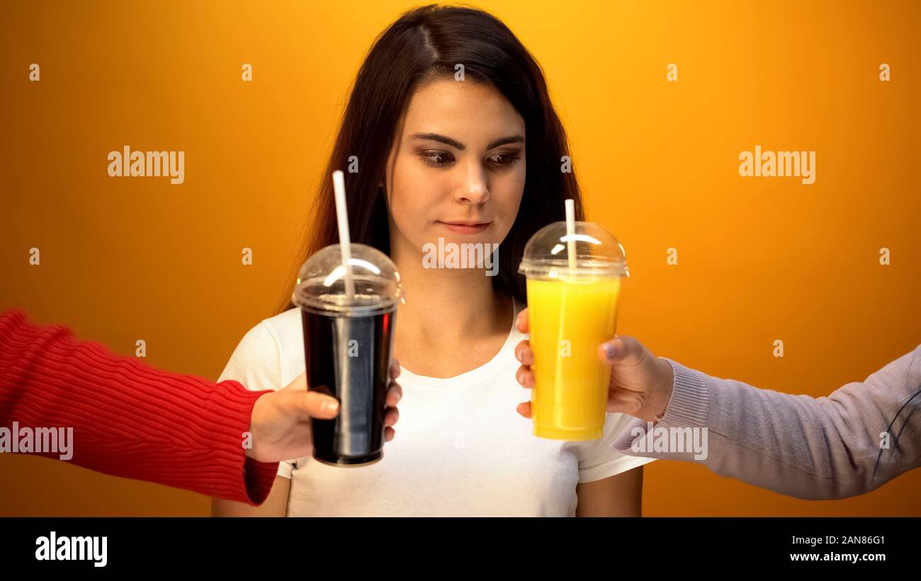 Girl choosing between orange juice and soda, vitamin drink or unhealthy
