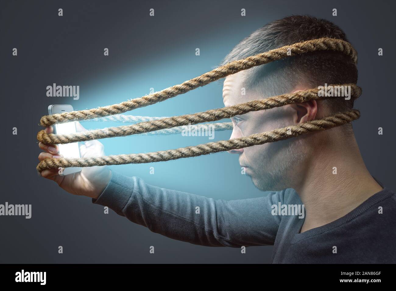 Man tied to his smartphone with a rope Stock Photo