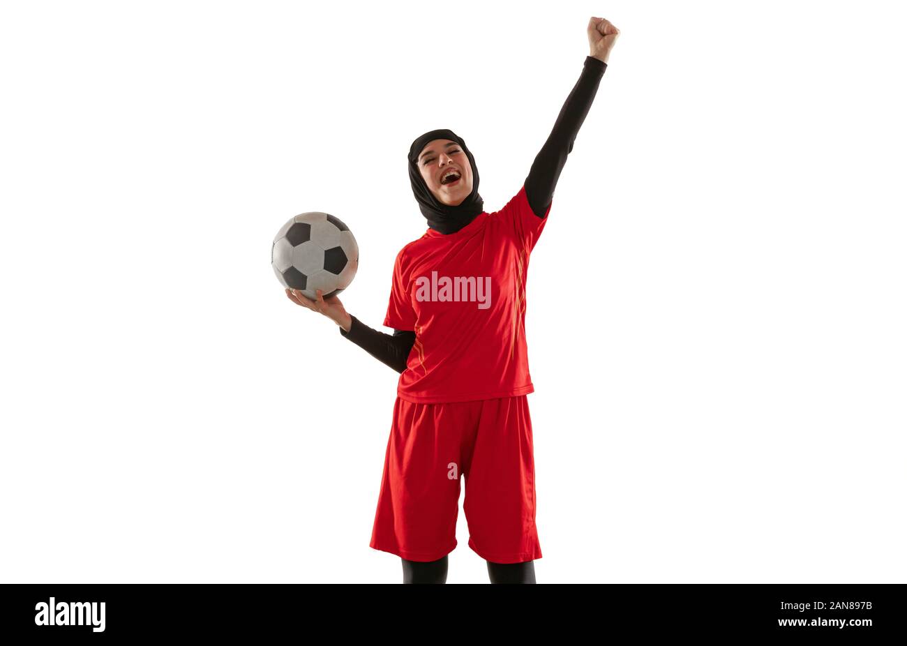 Emotions. Arabian female soccer or football player on white studio background. Young woman celebrating goal or match winning, catched in motion, action. Concept of sport, hobby, healthy lifestyle. Stock Photo
